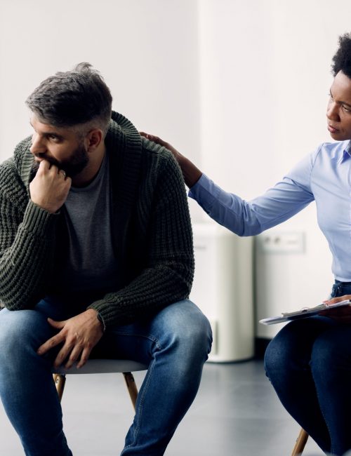 African American psychotherapist encouraging a man to talking about his problems during group therapy.