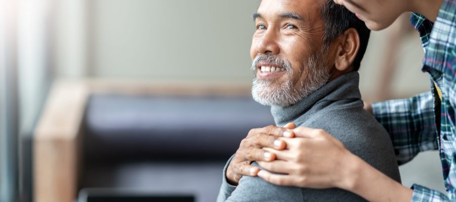 Smiling happy older asian father with stylish short beard touching daughter's hand on shoulder looking and talking together with love and care. Family relationship with bond and care concept.