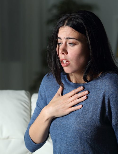 Woman suffering an anxiety attack alone in the night on a couch at home