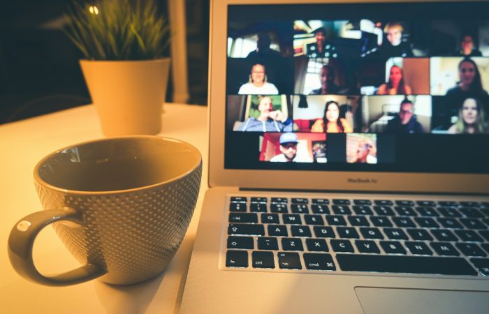 A laptop screen shows several people taking part in a video meeting