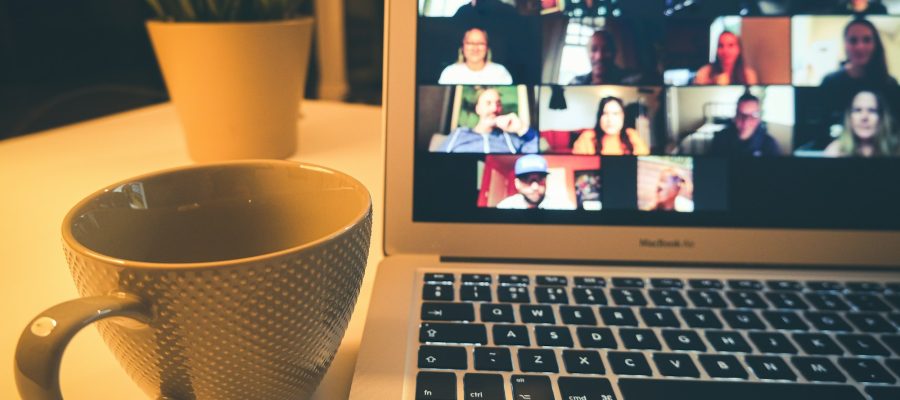 A laptop screen shows several people taking part in a video meeting