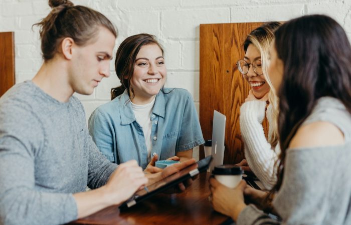 Three adults talk together over drinks at a table
