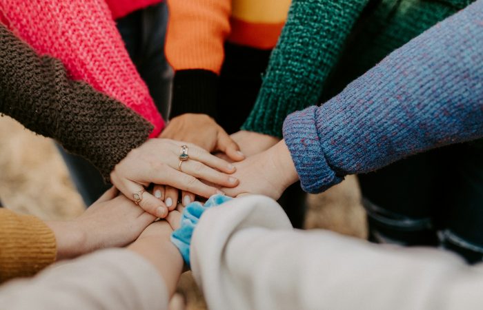 Several people bring their hands together in a circle