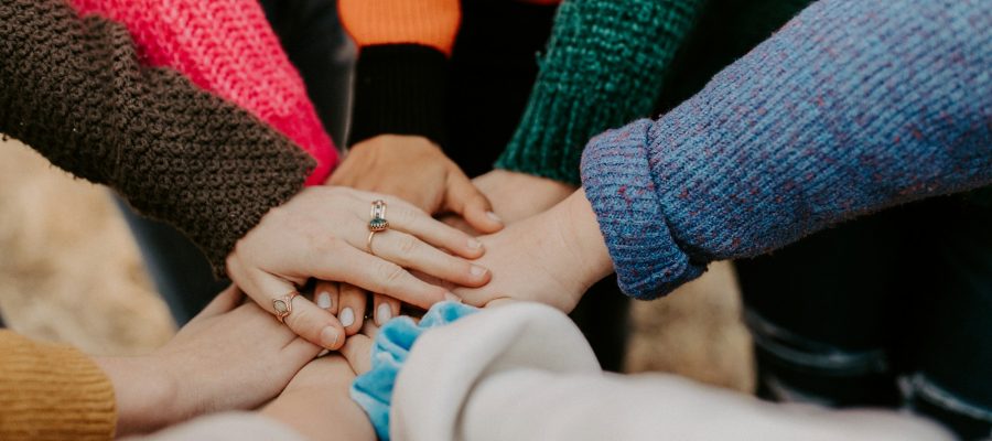 Several people bring their hands together in a circle
