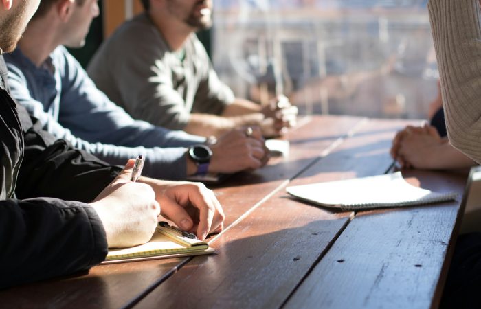 People discuss notes and documents around a shared table