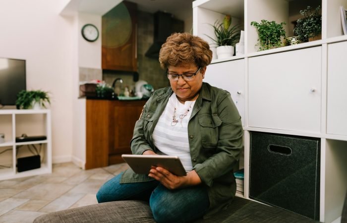 An older woman uses a tablet at home