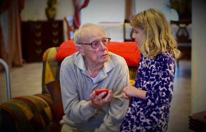 An older man and an adult woman talk indoors