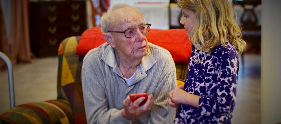 An older man and an adult woman talk indoors
