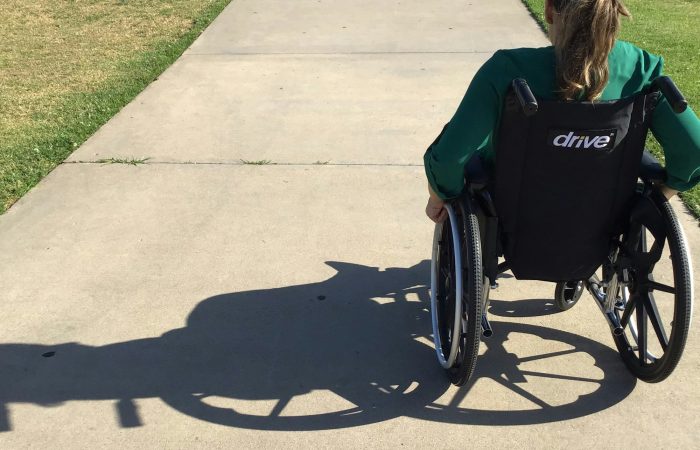 A person uses a wheelchair on an outdoor path