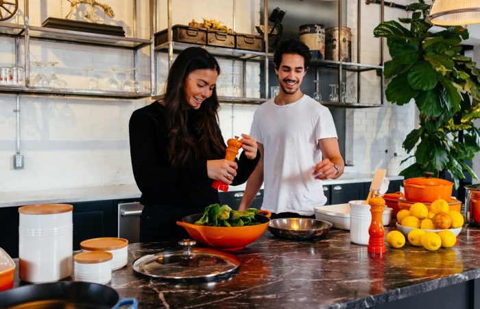 Two adults prepare vegetables together in a kitchen