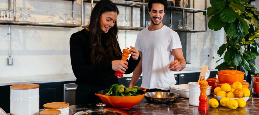 Two adults prepare vegetables together in a kitchen