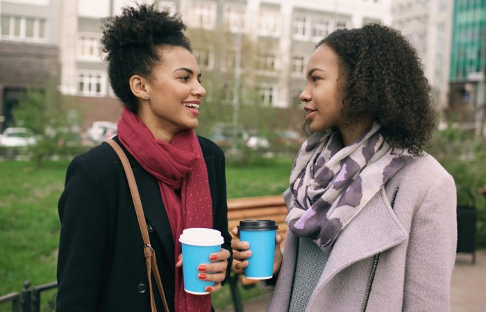 Two women talk over takeaway coffee outdoors