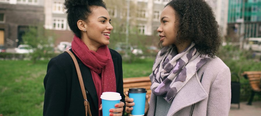 Two women talk over takeaway coffee outdoors