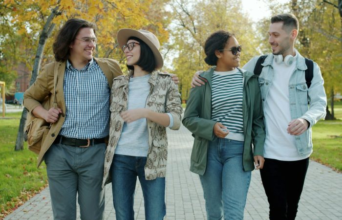 Four adults walk together along a path outdoors