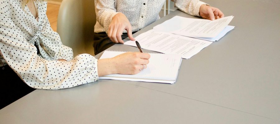 Two women review and sign a document at a table