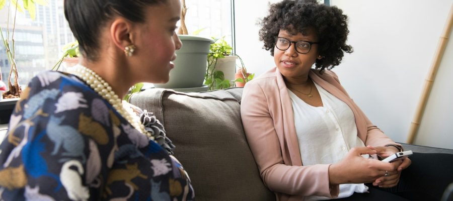 Two women talk together in a bright room
