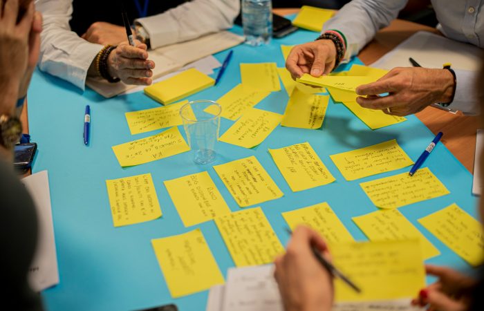 People arrange handwritten notes on a table during a workshop