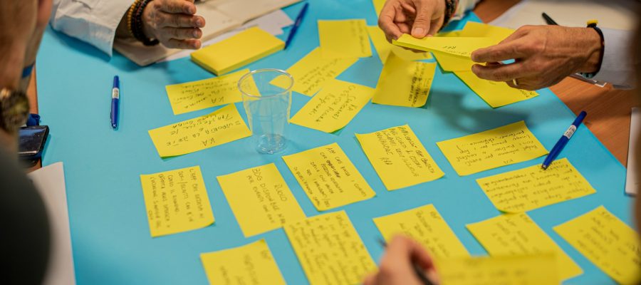 People arrange handwritten notes on a table during a workshop