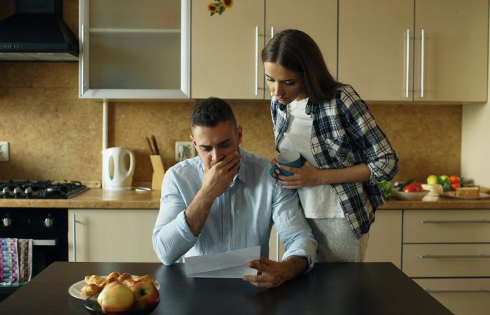 Two adults look at household paperwork in a kitchen