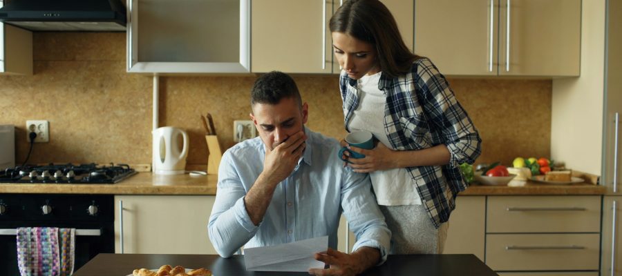 Two adults look at household paperwork in a kitchen