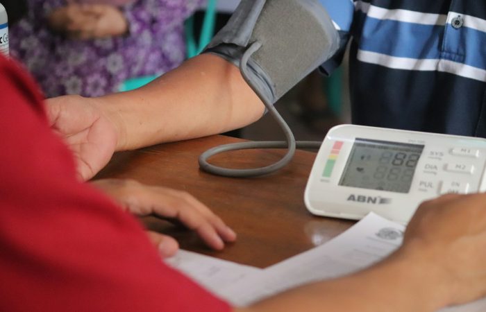An adult has their blood pressure checked at a table