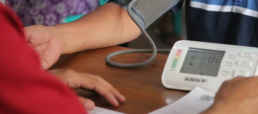 An adult has their blood pressure checked at a table